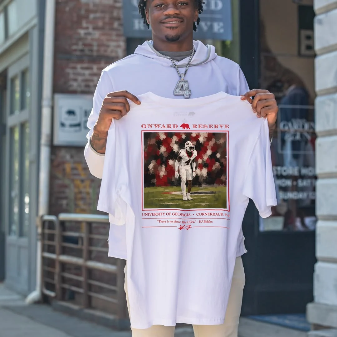 KJ Bolden holding his White Out tee outside Onward Reserve